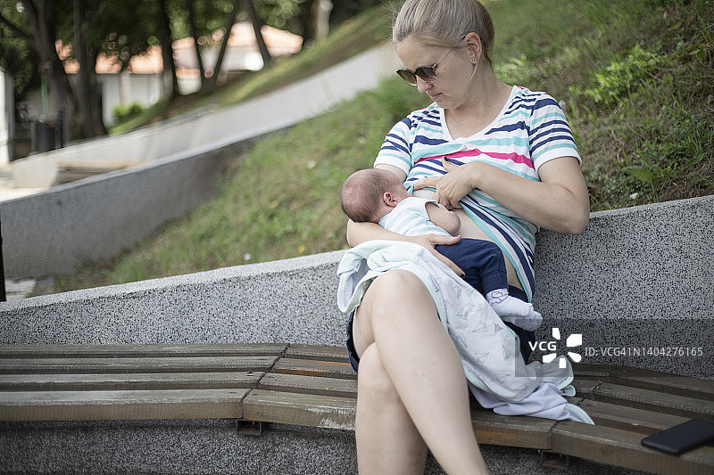 年轻妈妈在公共场所给男婴喂母乳图片素材