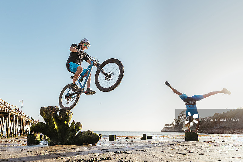 年轻情侣在沙滩上表演特技图片素材