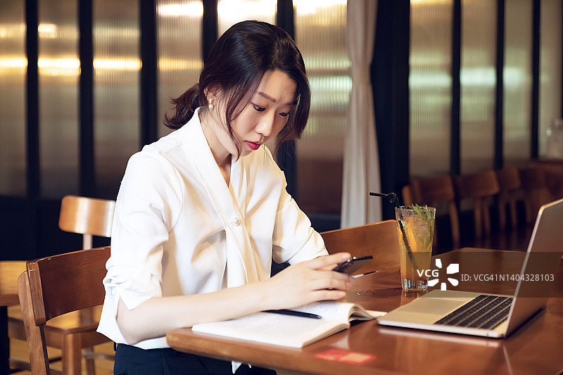 年轻女子在咖啡馆用手机查找信息图片素材