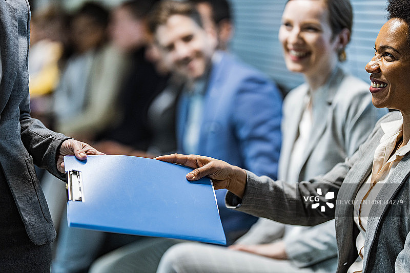 快乐的黑人候选人在等候室向人力资源团队成员提供文件图片素材