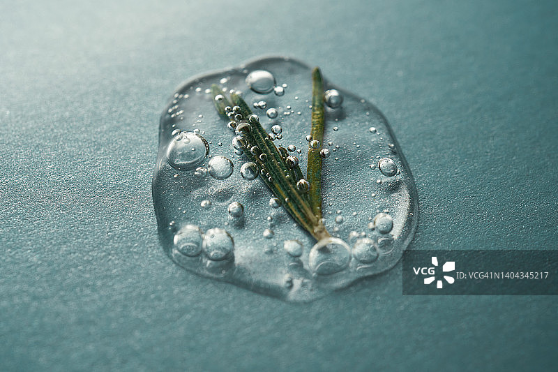 一滴含有迷迭香的化妆品凝胶，绿色背景图片素材