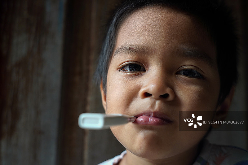 嘴里含着温度计的生病小男孩图片素材