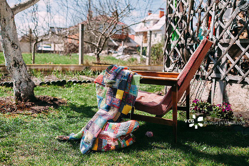 花园旧椅上的彩色手工针织毯图片素材
