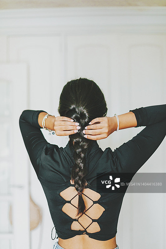 在家编辫子的年轻拉丁裔女子背影图片素材