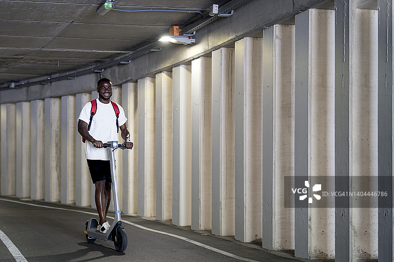 年轻男人在隧道骑电动滑板车图片素材