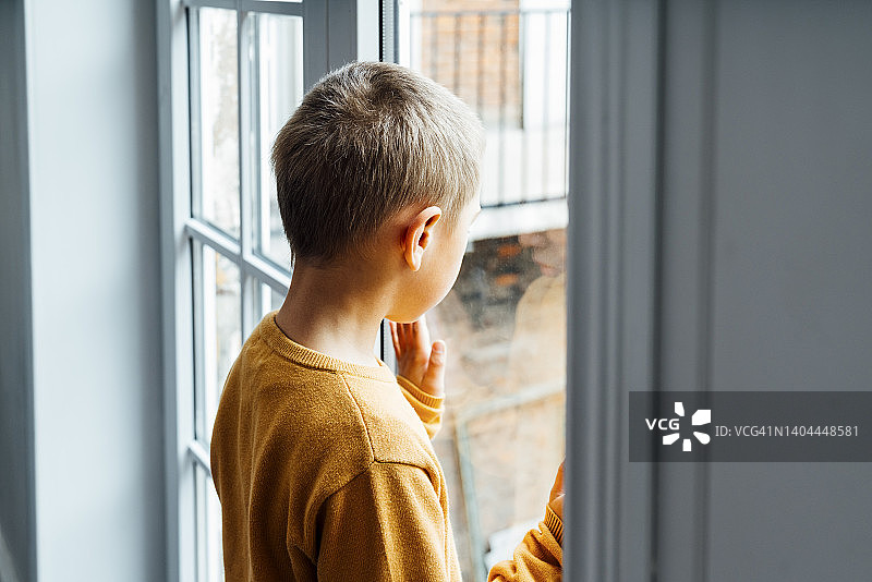 男孩在家看着窗外图片素材
