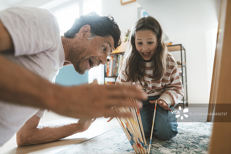 惊讶的父亲和女儿在家玩米卡多游戏图片素材