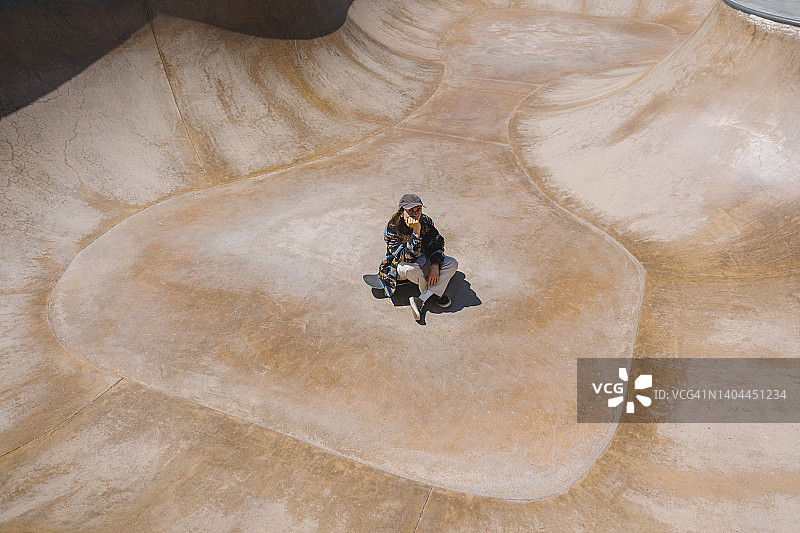 坐在运动坡道滑板上的年轻女人图片素材