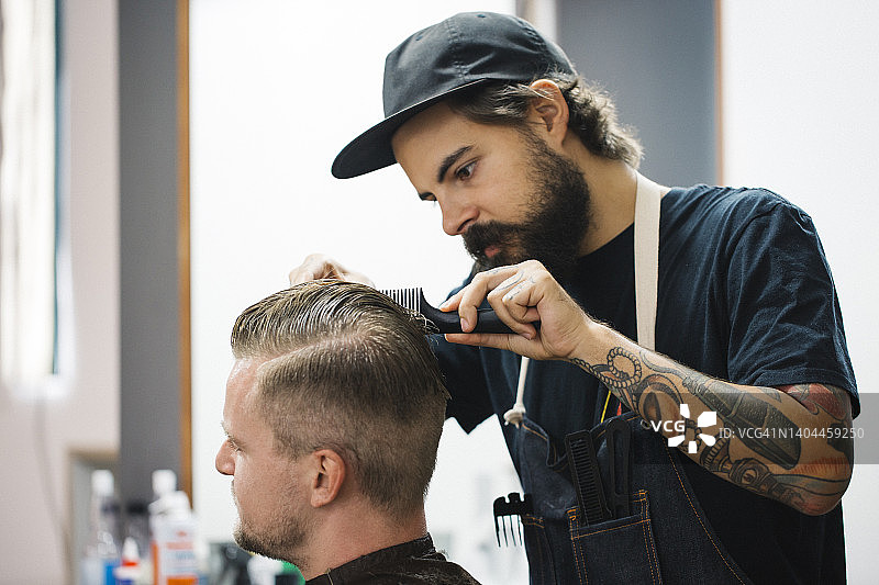 年轻的发型师在理发店为顾客做发型图片素材