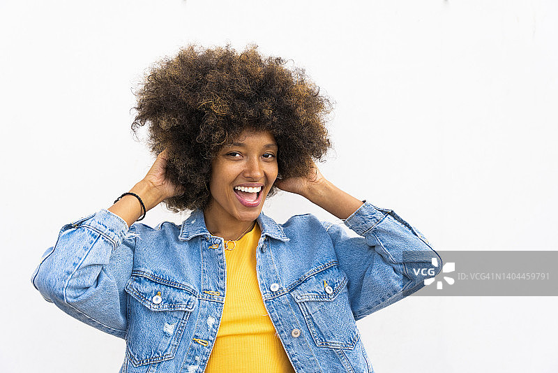 快乐的非洲裔女人站立，双手放在头发上图片素材