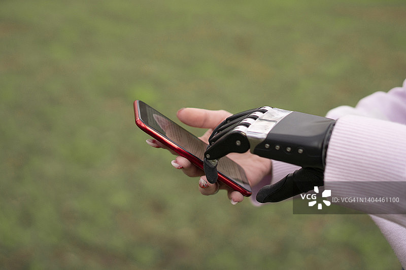 手持装有假肢手机的年轻女人图片素材