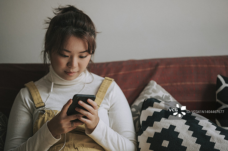 在家休闲的穿着工装连体裤的亚裔中国籍年轻女子图片素材