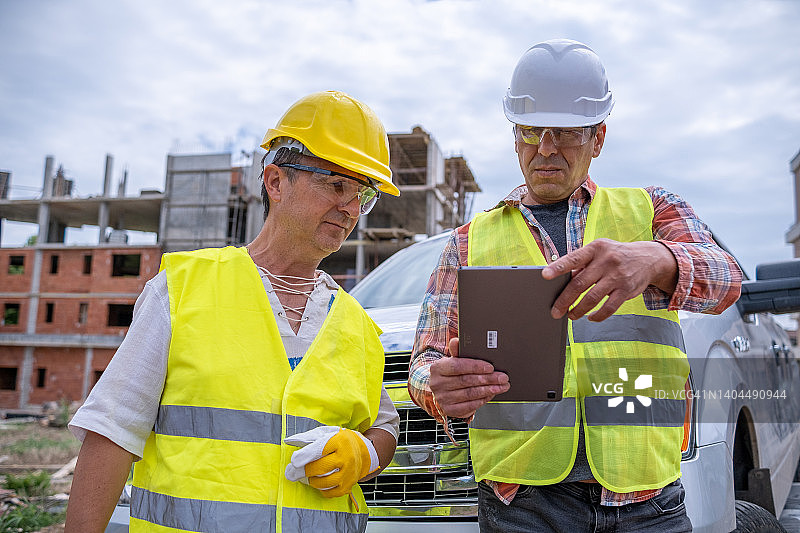 建筑业 предприниматель 和建筑工人在建筑工地观看数字平板电脑图片素材