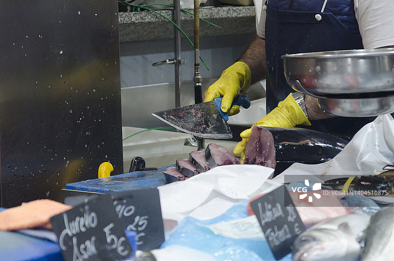 鱼市中戴蓝色围裙的鱼贩正在处理金枪鱼图片素材