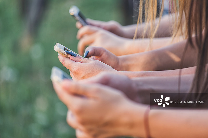 朋友们在户外使用智能手机图片素材