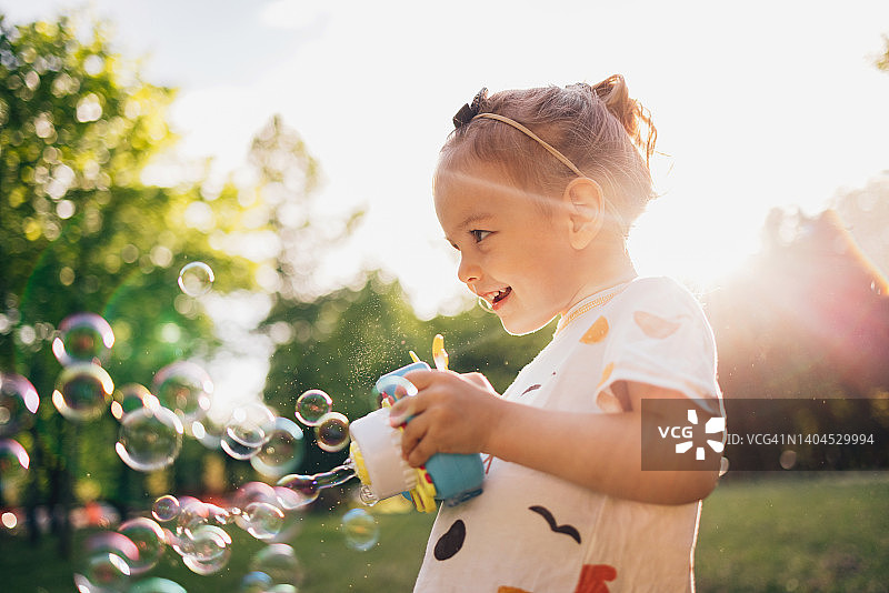 在公园里吹泡泡玩耍的快乐年轻女孩图片素材