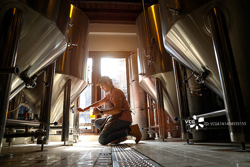 英俊的酿酒师闻着新鲜酿造的啤酒图片素材