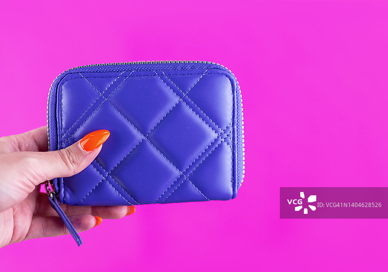 女子在粉色背景前手持紫色钱包图片素材