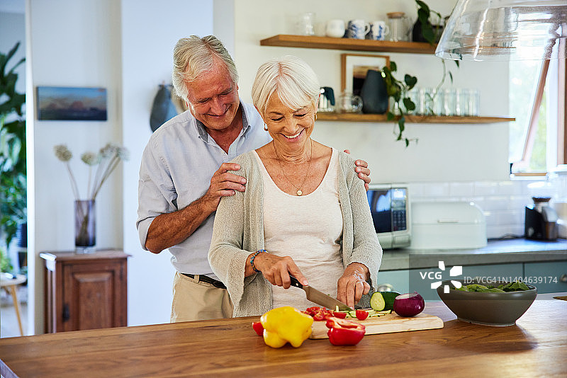 笑容满面的老年妇女和她的丈夫在厨房准备健康的午餐图片素材