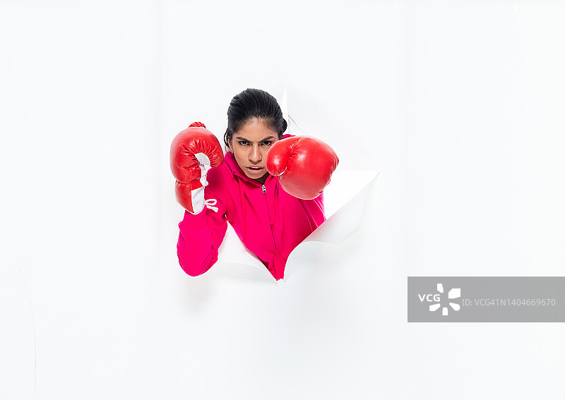 Z世代女性，戴着拳击手套站在白色背景前图片素材