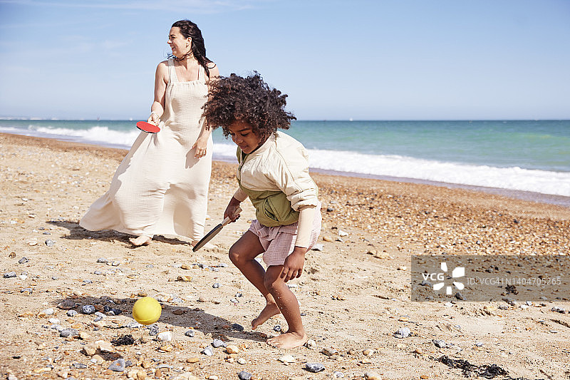 在海滩上玩球拍和球的母子，家庭沿海公路旅行图片素材
