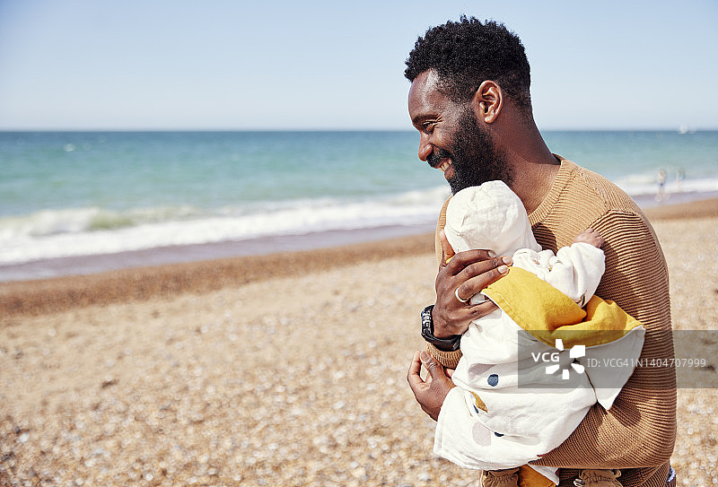 阳光明媚的海滩之旅，父亲抱着新生女婴开怀大笑图片素材