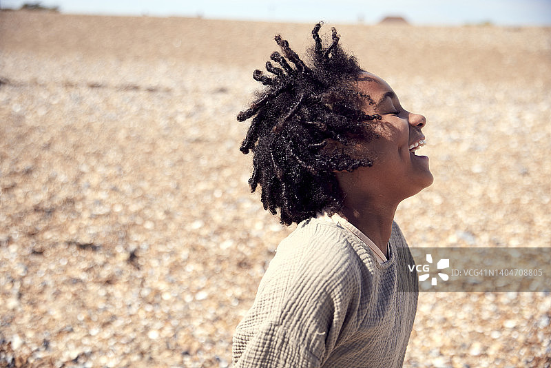 在淡季的海滩上享受家庭日，欢笑回头的7岁男孩图片素材