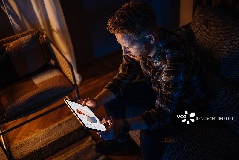 一位姜黄色头发的男商人正在平板电脑上查看公司财务分析，面露担忧图片素材