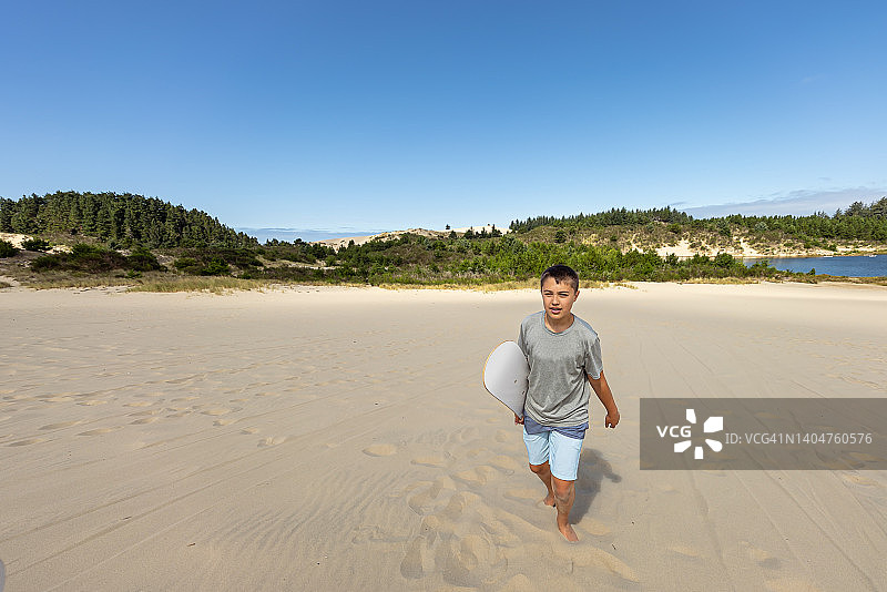 少年在家庭度假时享受滑沙的乐趣图片素材