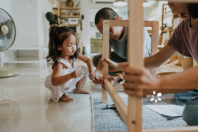 在父母的帮助下尝试组装家具的小女孩图片素材