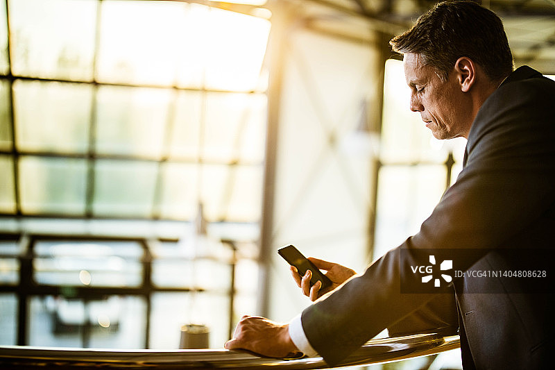 中年男企业家在走廊里用手机阅读短信图片素材