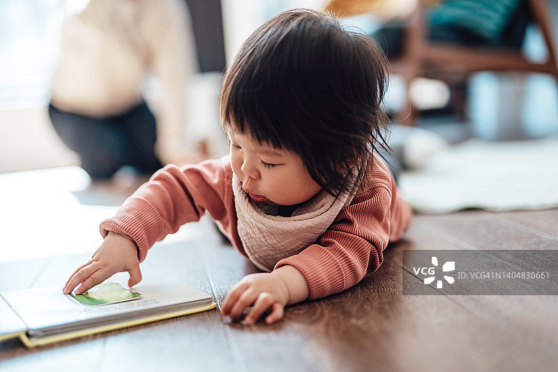 躺在地板上看书的可爱幼儿图片素材