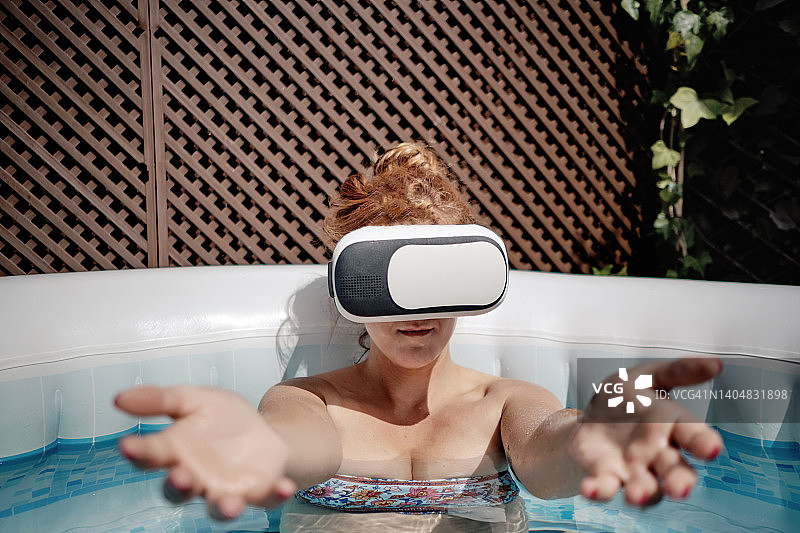 戴着VR眼镜，向相机伸出双臂的女人图片素材