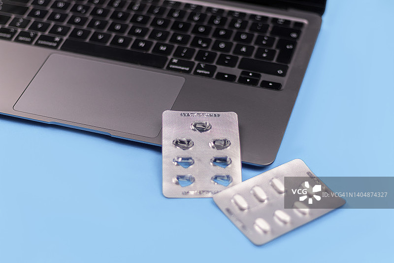 蓝色背景上的药丸泡罩和笔记本电脑图片素材