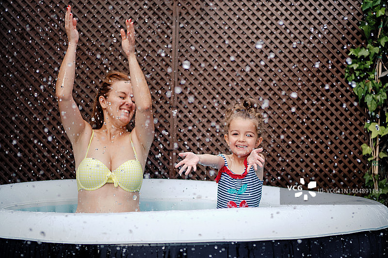母女在花园泳池里泼水图片素材