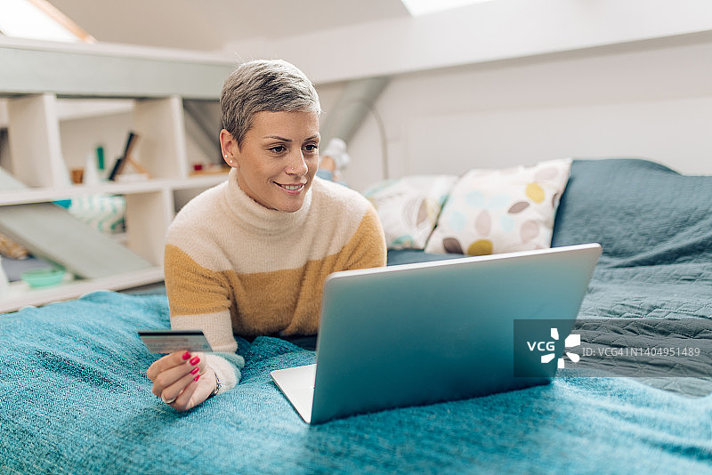 在床上进行网上银行的快乐女人图片素材