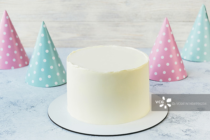 未装饰的蛋糕和彩色派对帽。图片素材