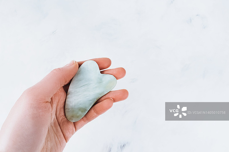 浅色背景上手持的绿色水粉刮刀图片素材