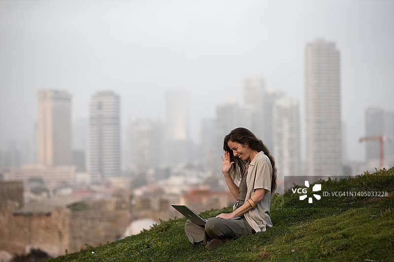 在城市景观前在户外用笔记本电脑工作的女人图片素材
