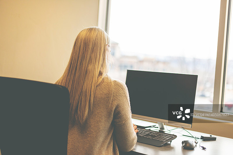中年女企业主在公司办公室办公桌前使用电脑工作图片素材
