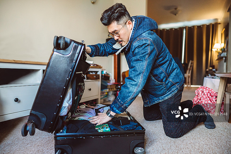 在家打包行李箱准备旅行的年轻亚洲男人图片素材