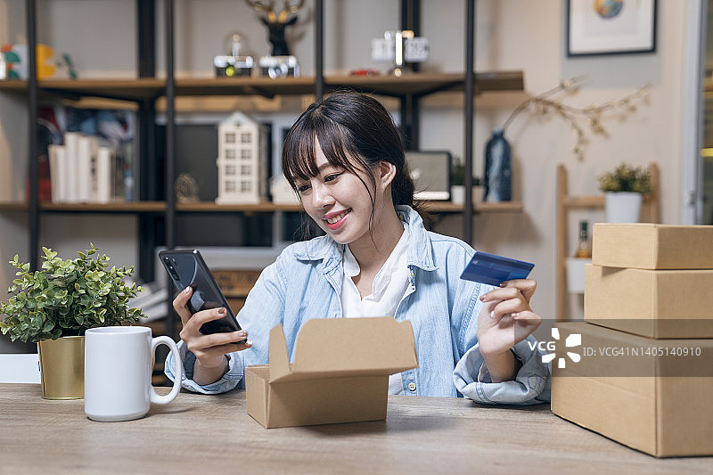 亚洲女人用智能手机在网上购物，并用信用卡进行移动支付图片素材
