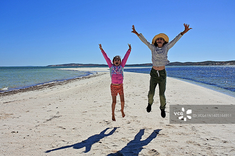 两个快乐的澳大利亚姐妹在公路旅行中跳跃图片素材