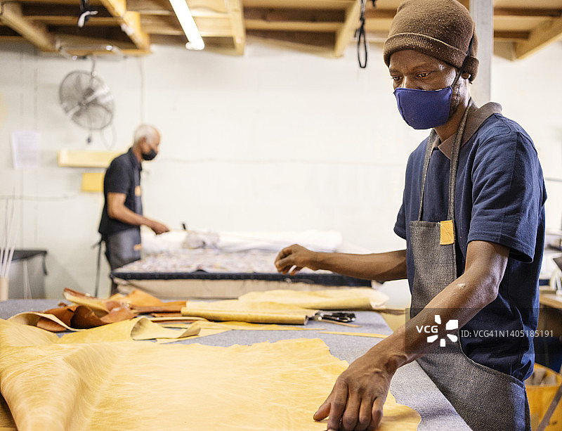 工人在家具作坊的工作台上整理布料图片素材