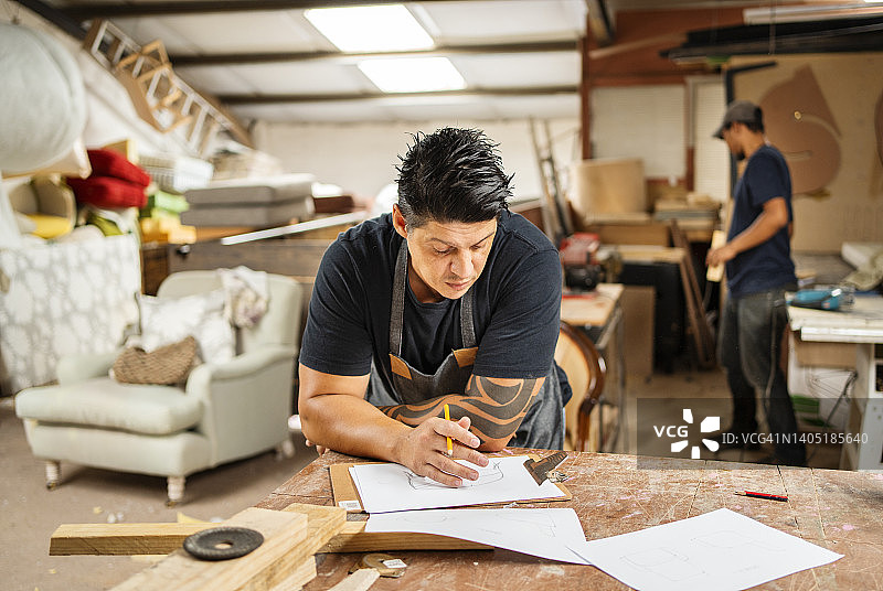 工人在家具制造车间的工作台上绘制设计草图图片素材