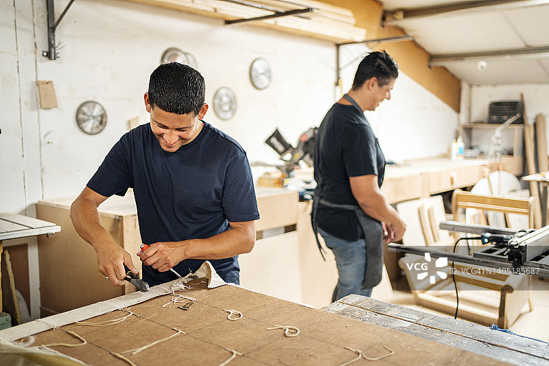 家具工坊里两位面带微笑在工作台前工作的男人图片素材
