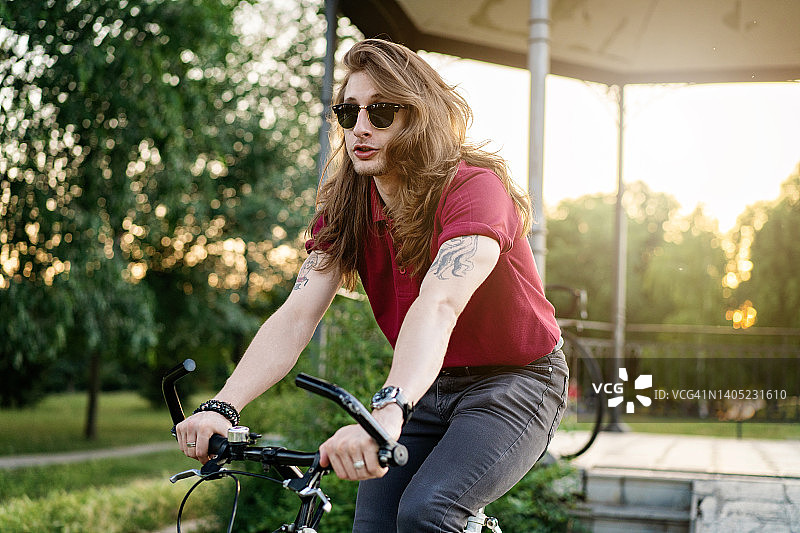 英俊的年轻男子在晴朗的日子里骑自行车图片素材