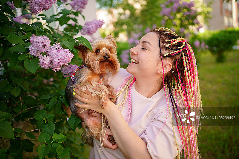 抱着约克夏犬，周围鲜花盛开的微笑女人图片素材