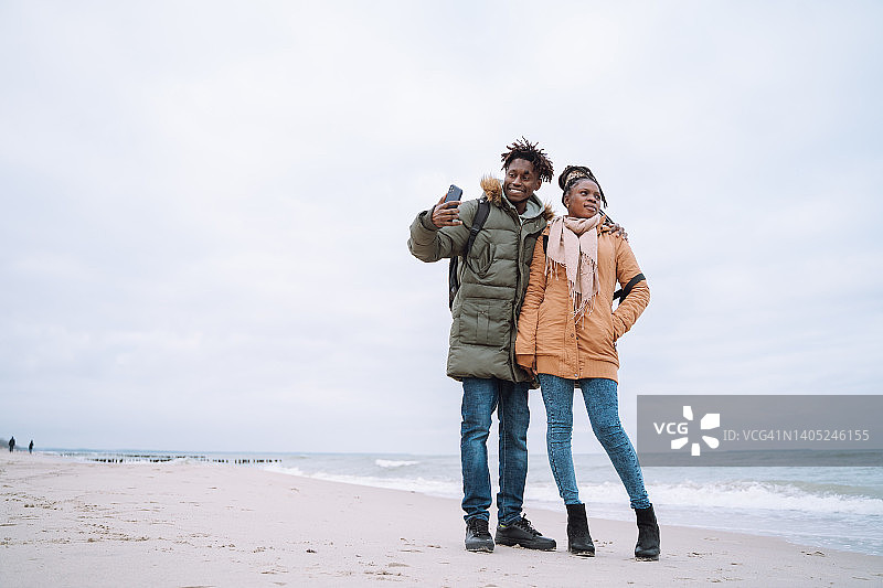 浪漫的非裔美国情侣合影自拍，微笑的男人和他的女朋友望着海平线图片素材