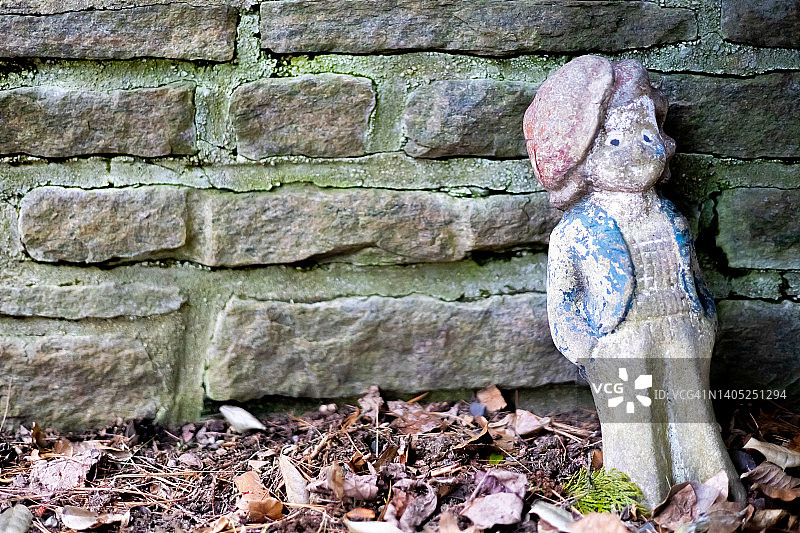 靠在石墙上的复古木制花园侏儒图片素材